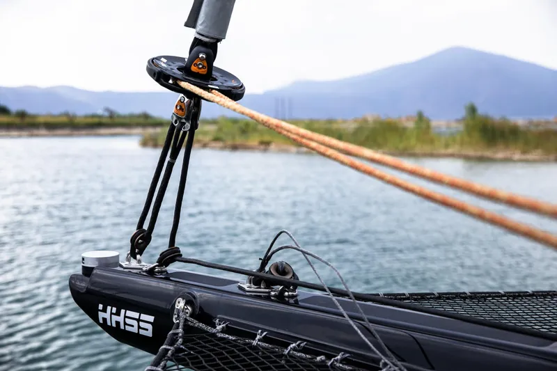  Yacht Photos Pics Bow of 2022 HH Catamarans HH55 with rigging, on calm water with mountain backdrop.