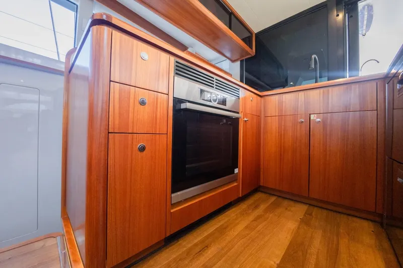  Yacht Photos Pics Modern kitchen interior of 2022 HH Catamarans HH55 with wood cabinetry and built-in oven.