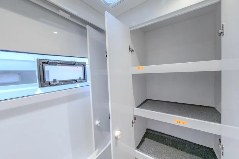  Yacht Photos Pics Spacious storage cabinet inside 2022 HH Catamarans HH55, featuring multiple shelves and a window.