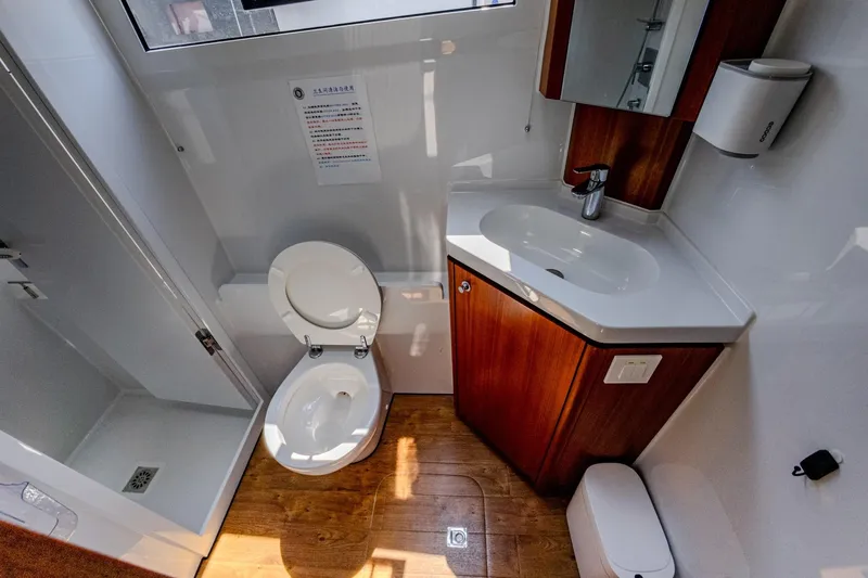  Yacht Photos Pics Modern bathroom in 2022 HH Catamarans HH55, featuring shower, toilet, and sink with wood accents.