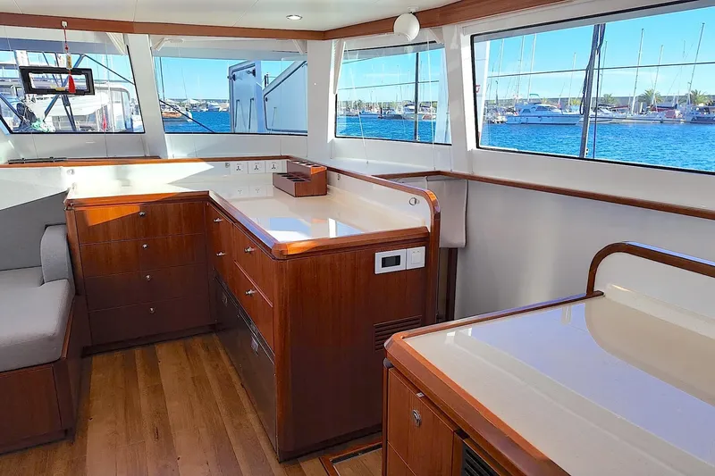  Yacht Photos Pics Luxurious interior of 2022 HH Catamarans HH55 with elegant wood cabinetry and panoramic windows.
