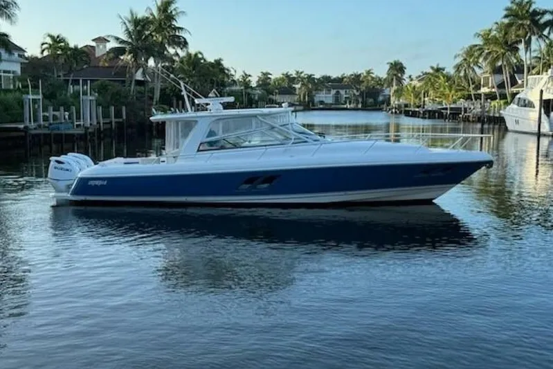 Saga Yacht Photos Pics 2019 Intrepid 430 Sport Yacht on calm water, surrounded by palm trees.