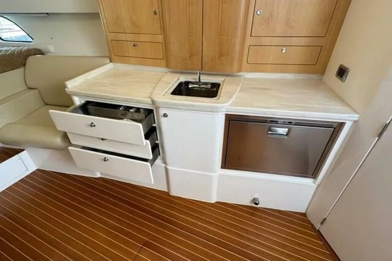 Saga Yacht Photos Pics 2019 Intrepid 430 Sport Yacht interior with kitchenette, featuring sink, drawers, and wood cabinetry.