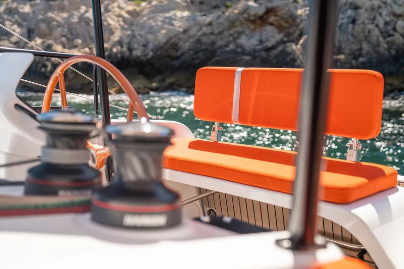  Yacht Photos Pics Luxurious 2026 Excess 13 yacht with vibrant orange seating, docked by rocky shoreline.
