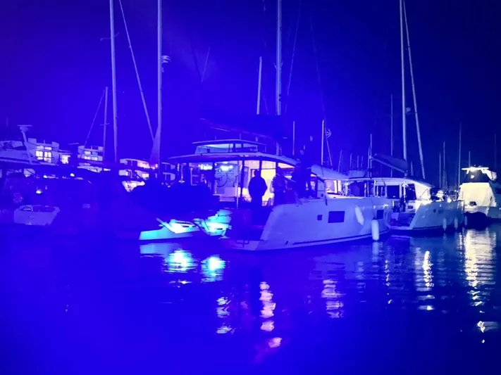 Alegria Yacht Photos Pics Night view of a 2020 Lagoon 42 catamaran illuminated by blue lights in a marina.