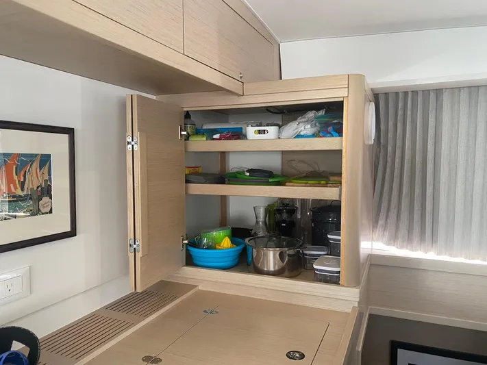 Alegria Yacht Photos Pics Interior of 2020 Lagoon 42 yacht with open kitchen cabinet displaying cookware and utensils.