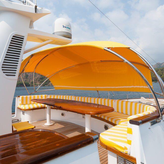Luxurious Codecasa 26m yacht deck with yellow canopy and striped seating, 1984 model.