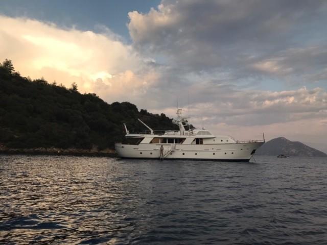 A 1984 Codecasa 26m yacht anchored near a scenic coastline at sunset.