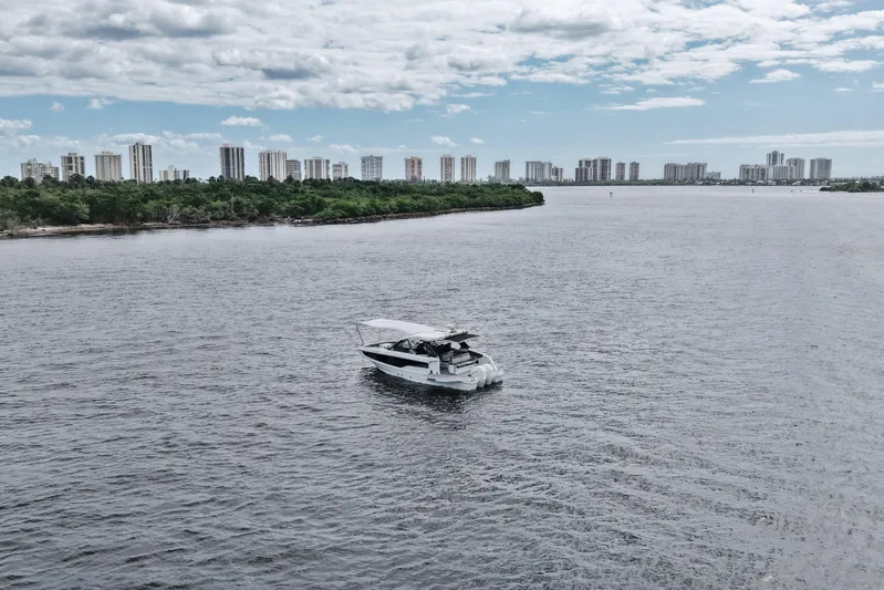  Yacht Photos Pics 2023 Galeon 400 XL yacht cruising on a wide river with city skyline backdrop.