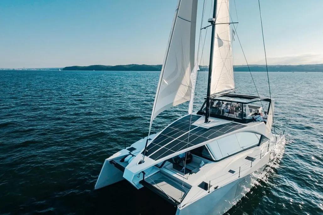 2024 Wave Wave60 catamaran sailing on open sea under clear blue sky.