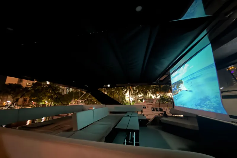  Yacht Photos Pics Luxurious 2024 Wave Wave60 yacht interior with outdoor seating and a large screen at night.