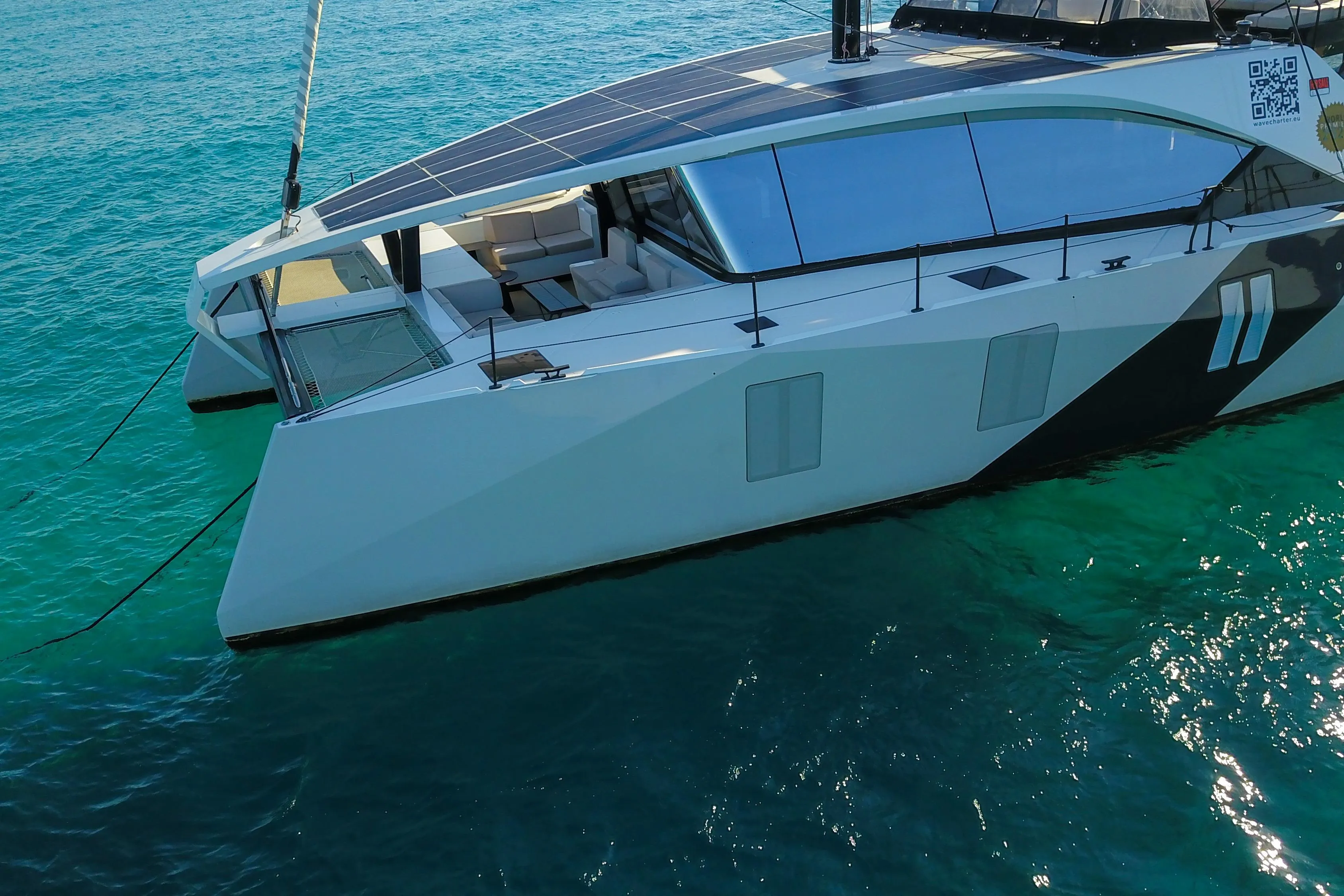 2024 Wave Wave60 catamaran with solar panels on turquoise water.