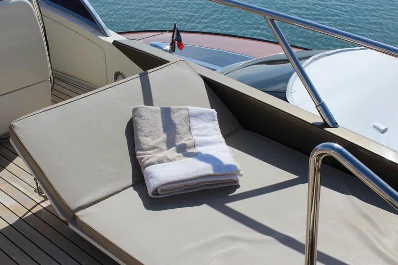 Happy Go Lucky Yacht Photos Pics Sunbathing area on 2009 Riva SportRiva 56 yacht with folded towels, wooden deck, and railing.