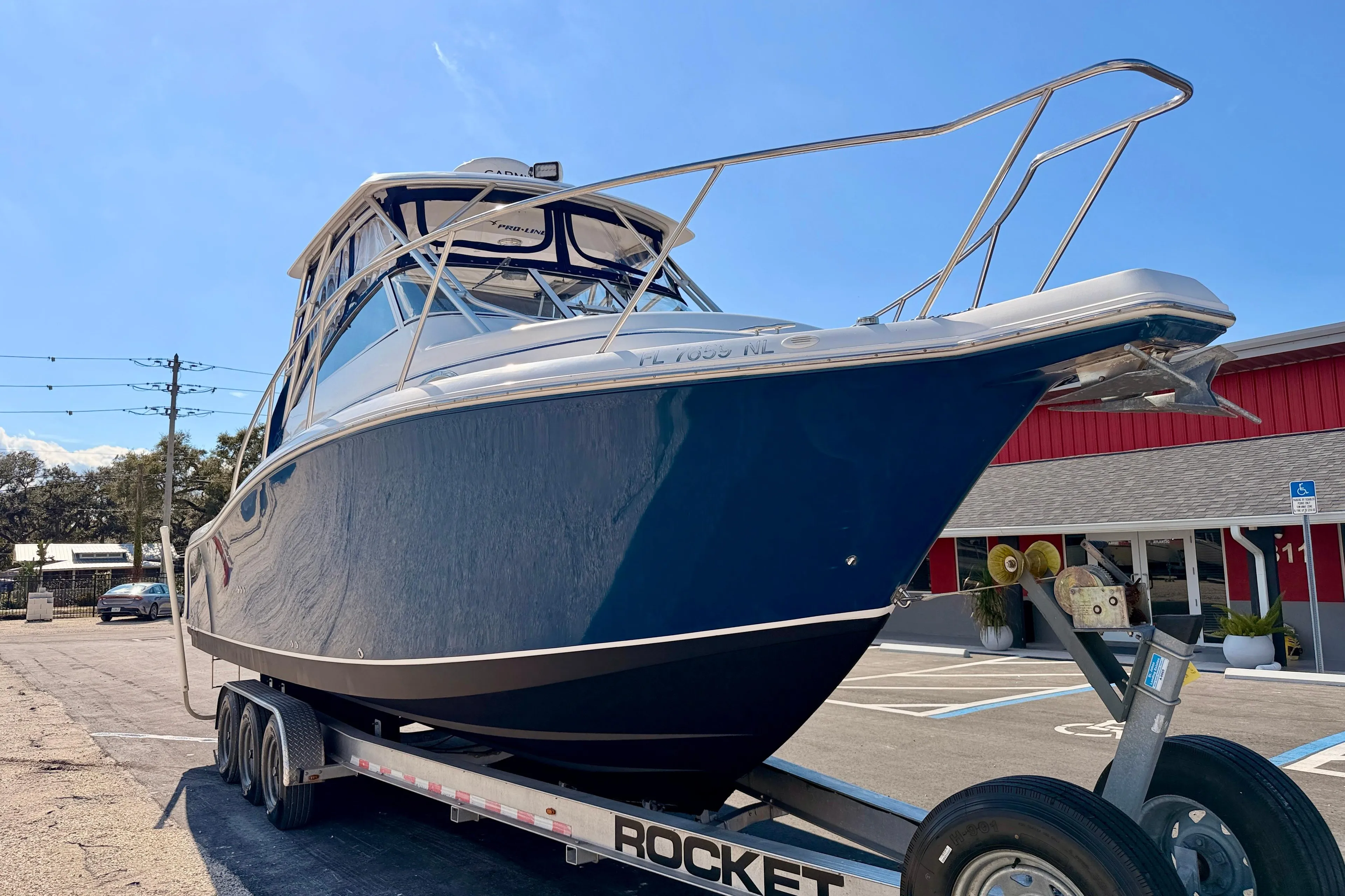 2007 Pro-Line 32 Express boat on trailer, parked outdoors under clear sky.