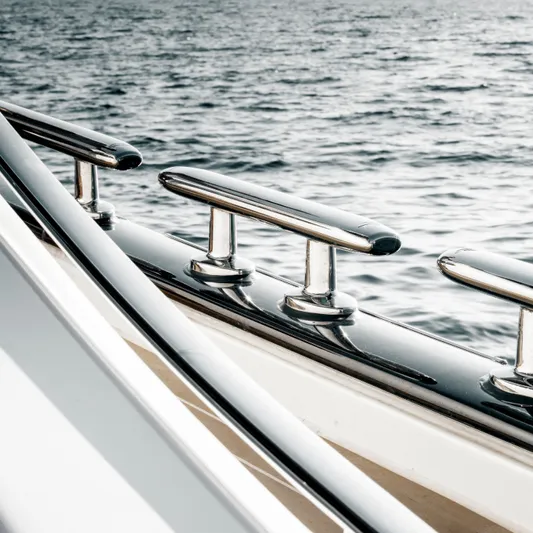 Tons Of Fun Yacht Photos Pics Close-up of 2022 Zeelander Z72 yacht's polished chrome railings by the water.