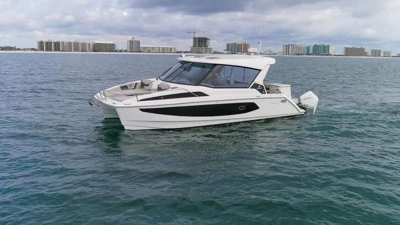  Yacht Photos Pics 2023 Aquila 36 Sport boat cruising on open water with city skyline in background.