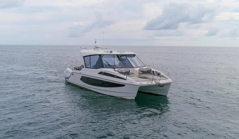  Yacht Photos Pics 2023 Aquila 36 Sport catamaran cruising on open sea under cloudy sky.