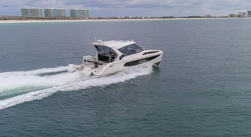  Yacht Photos Pics 2023 Aquila 36 Sport cruising on open water near coastal cityscape.