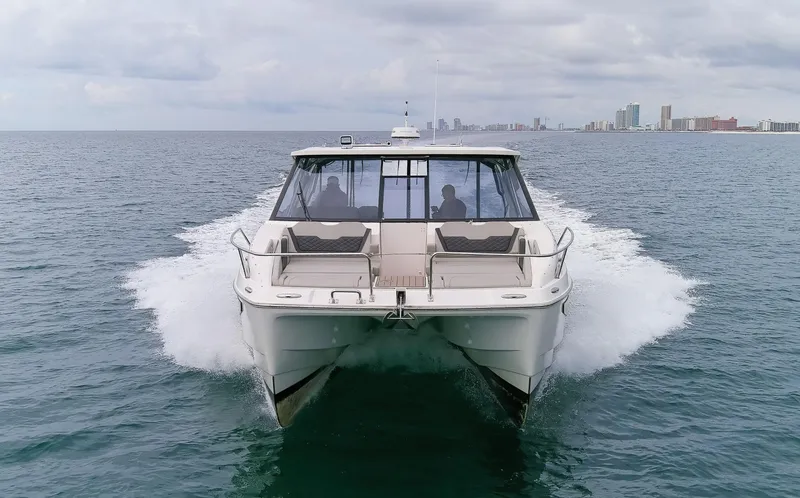  Yacht Photos Pics 2023 Aquila 36 Sport catamaran cruising on open water with city skyline in background.