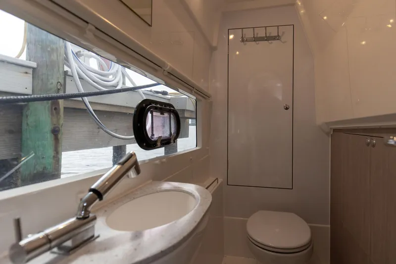  Yacht Photos Pics 2023 Aquila 36 Sport boat bathroom with sink, toilet, and window view.
