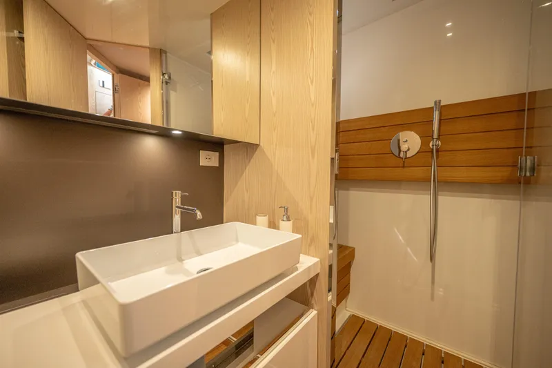 V-adeus Yacht Photos Pics Modern bathroom in 2024 SACS Rebel 55 yacht with sleek sink and wooden shower accents.