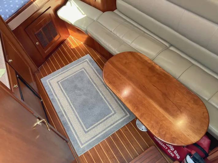 Alibi Yacht Photos Pics 2006 Rampage Express Offshore Tower interior with wooden table, beige seating, and a blue rug.
