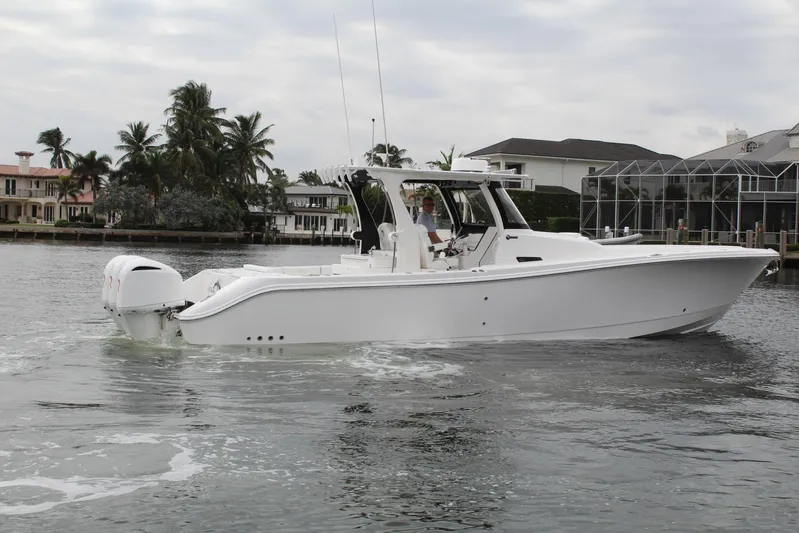  Yacht Photos Pics 2019 Edgewater 370CC boat cruising on a calm waterfront with palm trees.