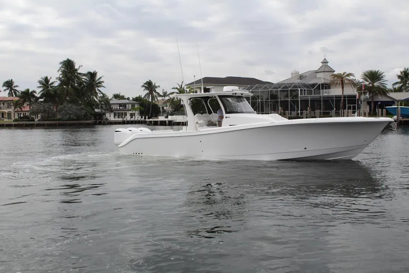  Yacht Photos Pics 2019 Edgewater 370CC boat cruising on a calm waterfront with palm trees.