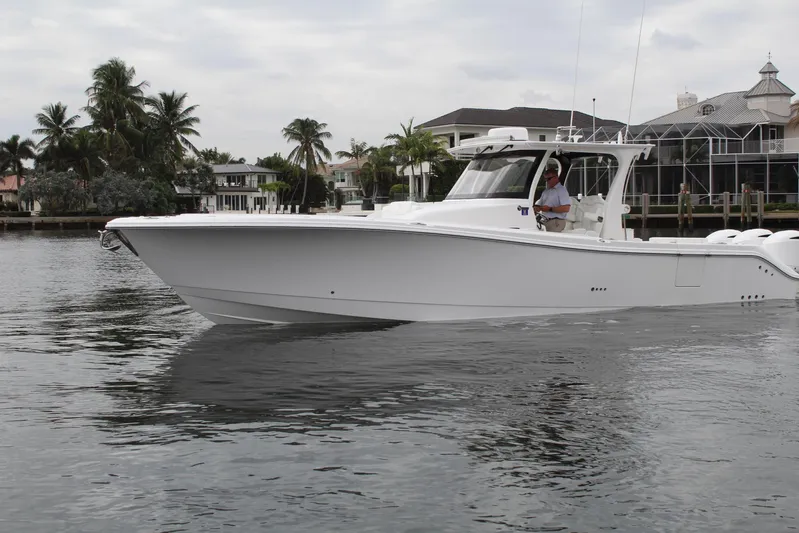  Yacht Photos Pics 2019 Edgewater 370CC boat cruising on a calm waterway near waterfront homes.