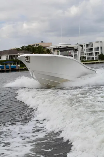  Yacht Photos Pics 2019 Edgewater 370CC boat cruising on water near waterfront buildings.