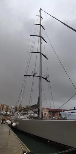 Syl Yacht Photos Pics Sleek 2003 custom sailboat with tall mast docked under cloudy skies.