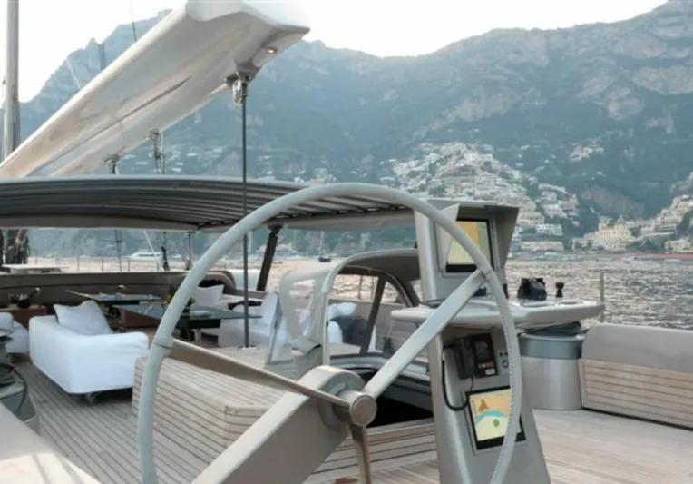 Syl Yacht Photos Pics Luxury yacht deck with steering wheel, overlooking coastal mountains and town.