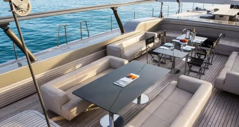 Syl Yacht Photos Pics Luxurious yacht deck with elegant seating and dining area, overlooking serene blue waters.