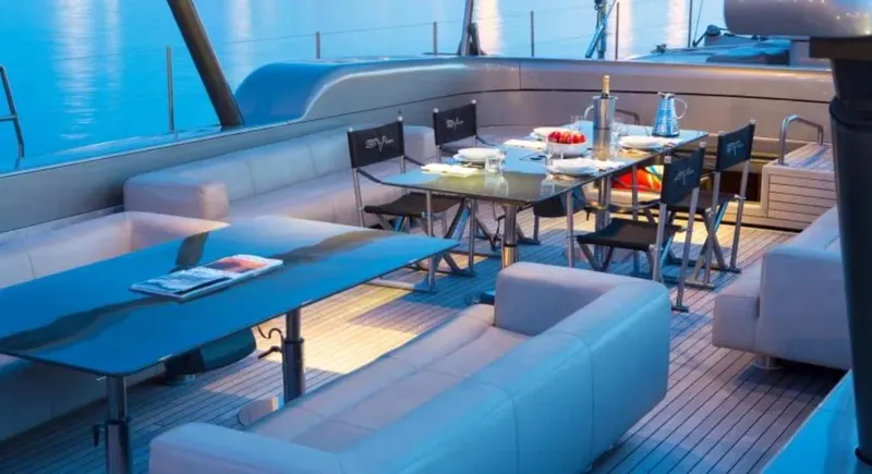 Syl Yacht Photos Pics Luxurious yacht deck with elegant dining setup, featuring modern furniture and serene ocean backdrop.