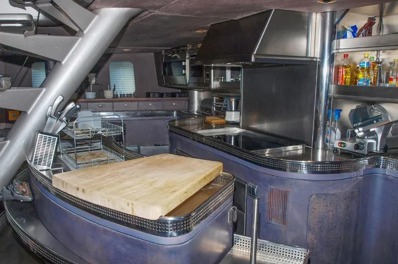 Syl Yacht Photos Pics Modern yacht kitchen with stainless steel appliances, wooden cutting board, and organized shelves.