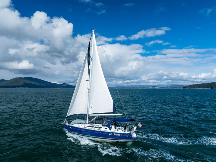 Salus Yacht Photos Pics Sailing yacht Jeanneau Sun Odyssey 40, 2001 model, cruising on open water under a blue sky.