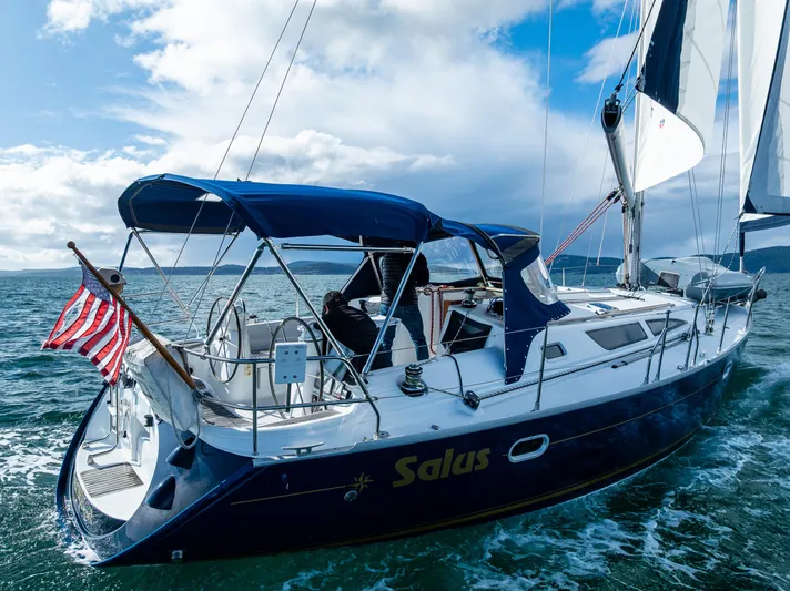 Salus Yacht Photos Pics Jeanneau Sun Odyssey 40 sailboat from 2001 sailing on open water with American flag.