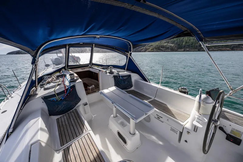 Salus Yacht Photos Pics 2001 Jeanneau Sun Odyssey 40 sailboat cockpit with blue canopy, steering wheel, and seating area.