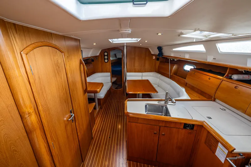 Salus Yacht Photos Pics Interior of 2001 Jeanneau Sun Odyssey 40 sailboat with wooden cabinetry and seating area.