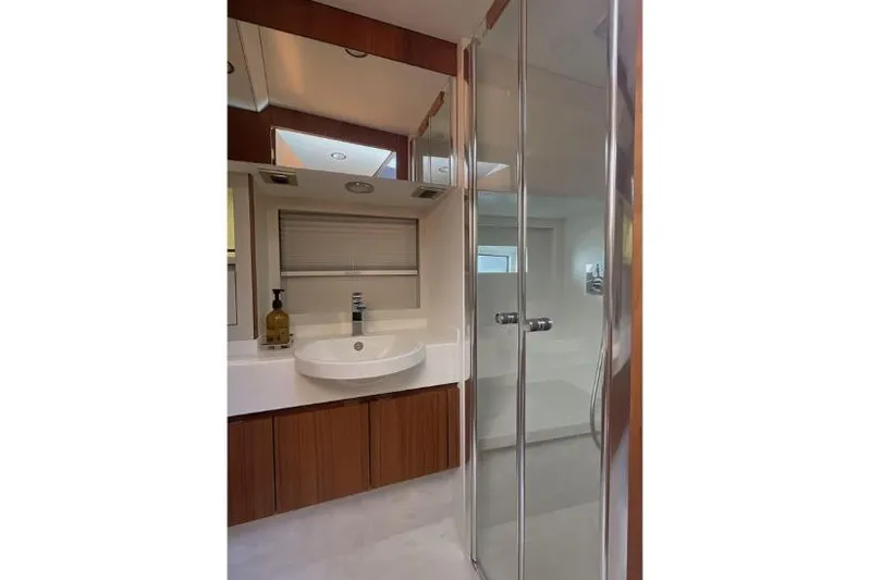  Yacht Photos Pics Modern bathroom in 2023 Glacier 48 model with glass shower and wooden cabinetry.