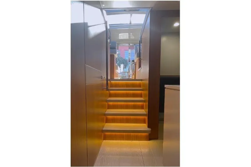  Yacht Photos Pics Illuminated wooden staircase inside 2023 Glacier 48 yacht, leading to upper deck.