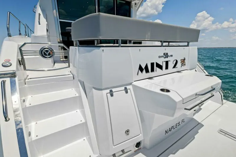 Mint 2 Bee Yacht Photos Pics 2022 Cruisers Yachts 50 Cantius, rear view, docked in Naples, FL, with "Mint 2" name.