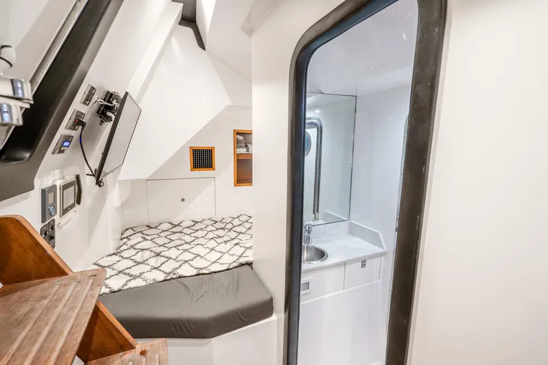 Mocean Yacht Photos Pics 2021 Ocean Alexander 70E Motoryacht cabin with bed, TV, and compact bathroom.