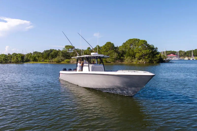 One More Yacht Photos Pics 2022 Contender 44 ST boat cruising on a scenic lake with lush greenery.
