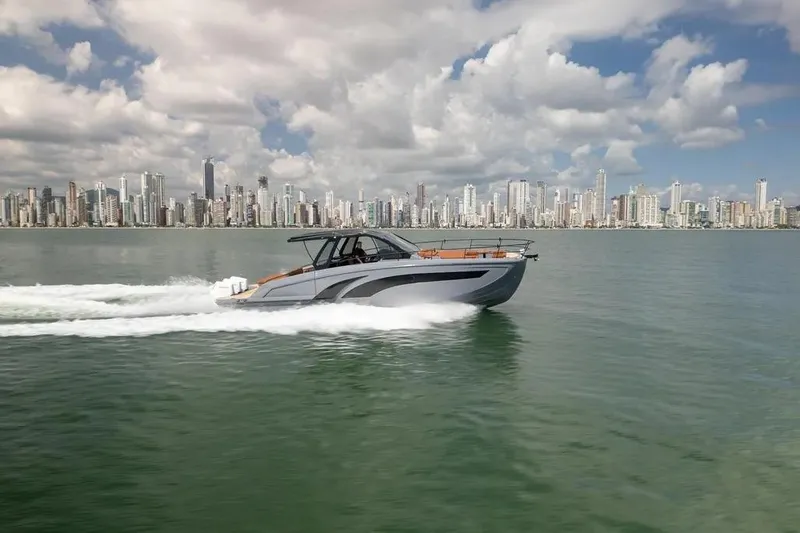  Yacht Photos Pics Luxury Hanover 447 yacht cruising near city skyline, 2025 model, under a partly cloudy sky.