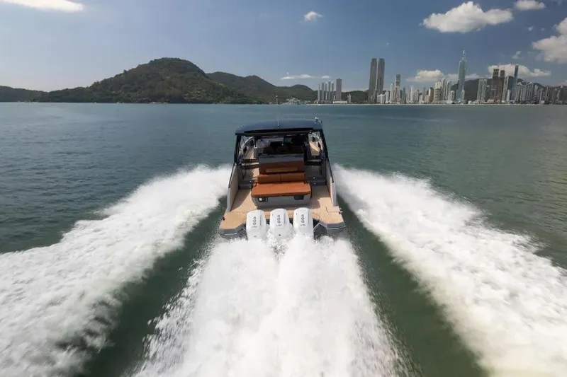  Yacht Photos Pics 2025 Hanover 447 Ultimate Luxury Edition yacht cruising near city skyline and mountains.