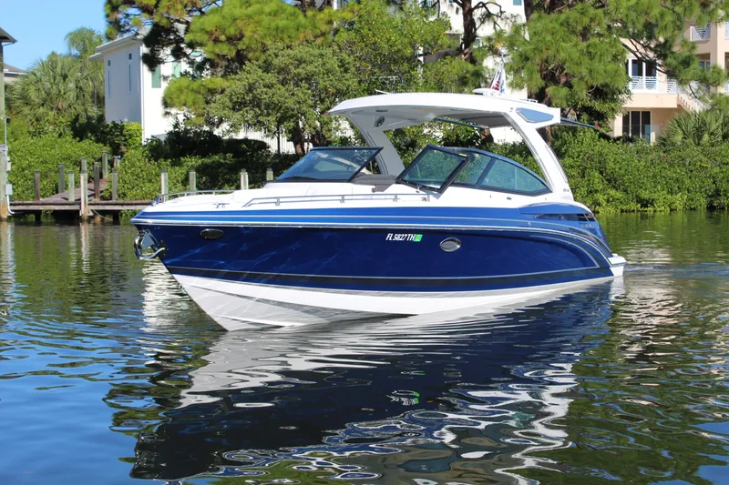  Yacht Photos Pics 2023 Formula 330 Crossover Bowrider on calm water, surrounded by lush greenery.