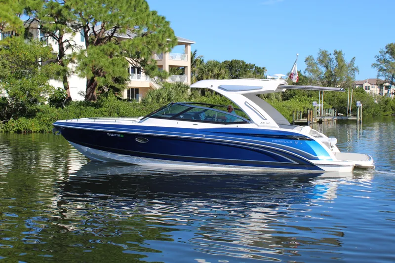  Yacht Photos Pics 2023 Formula 330 Crossover Bowrider on a serene waterway, surrounded by lush greenery.