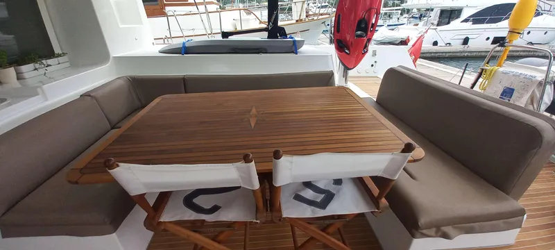 Amea Yacht Photos Pics Lagoon 52 F 2014 yacht deck with wooden table, cushioned seating, and marina view.