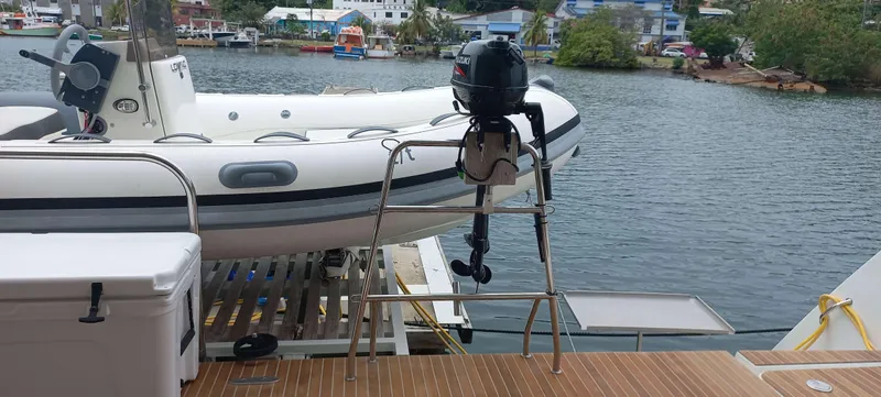 Amea Yacht Photos Pics Lagoon 52 F yacht with dinghy and outboard motor, docked by a scenic waterfront.